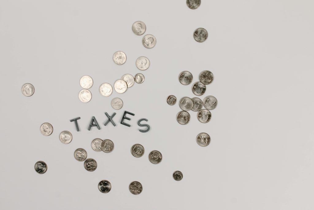 A visually striking flatlay of coins with 'Taxes' text on a white surface, ideal for financial concepts.